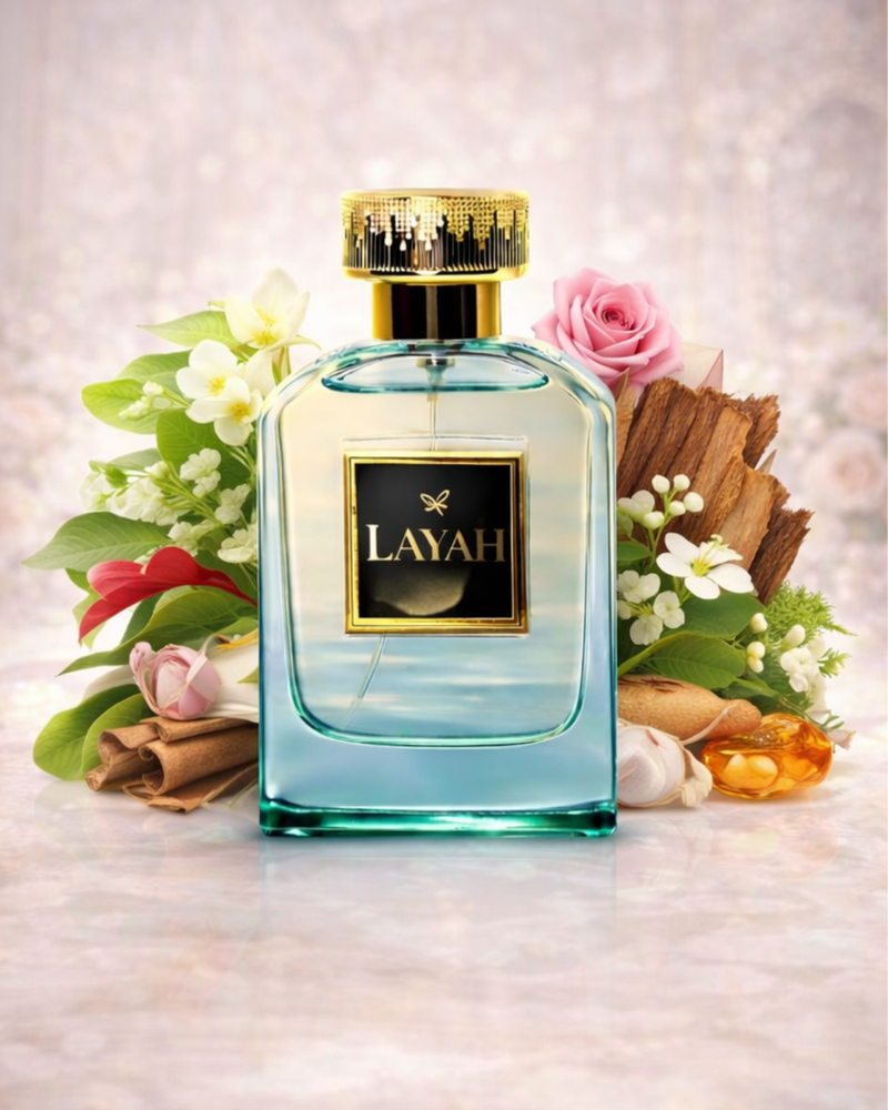 Perfume bottle with 'LAYAH' branding surrounded by flowers and cinnamon sticks on a light background