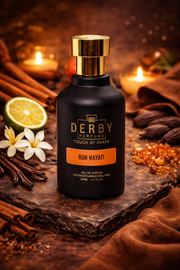 Black perfume bottle with gold cap on a dark surface with spices and flowers